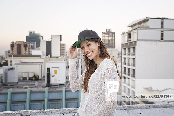 Junge Frau auf einer Dachterrasse stehend  lächelnd