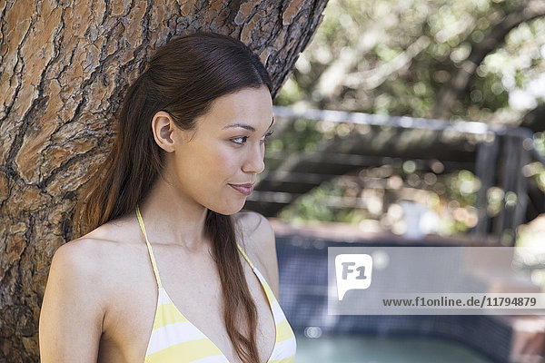 Young woman at tree at the poolside