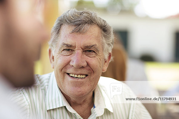 Smiling senior man socializing on a garden party