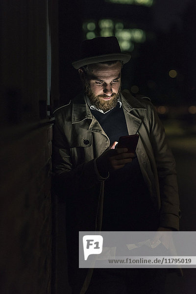 Stylish young man with cell phone in the city at night
