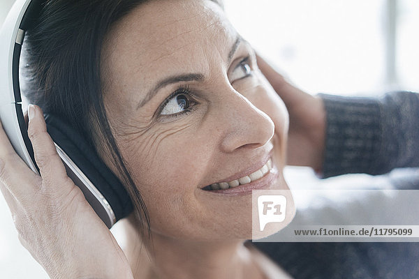 Porträt einer lächelnden Frau beim Musikhören mit Kopfhörern