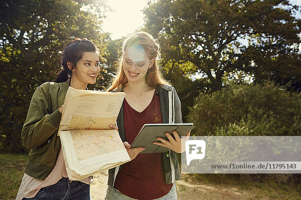 Zwei junge Frauen mit Tablette und Karte in der Natur