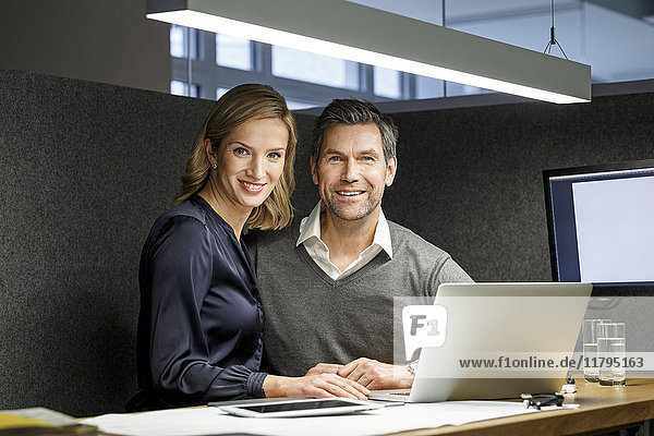 Porträt der lächelnden Geschäftsfrau und des Geschäftsmannes mit Laptop in der Meetingbox