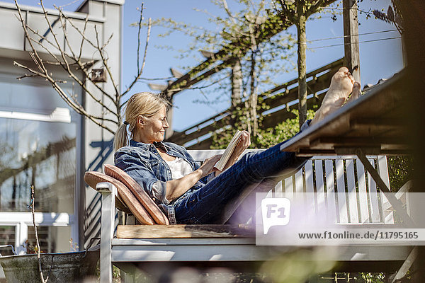 Smiling woman reading book on garden bench