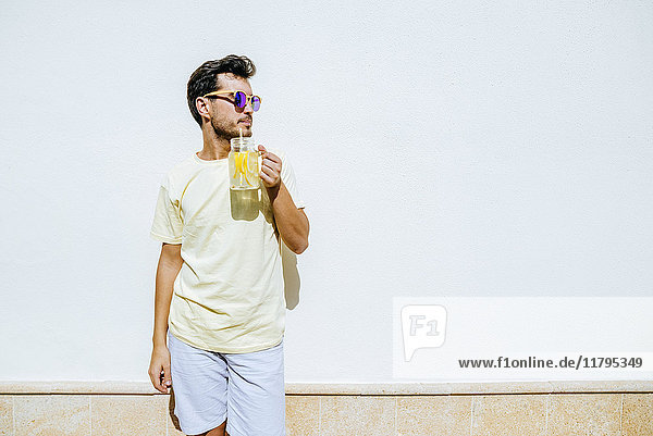 Man with sunglasses and lemonade in front white wall