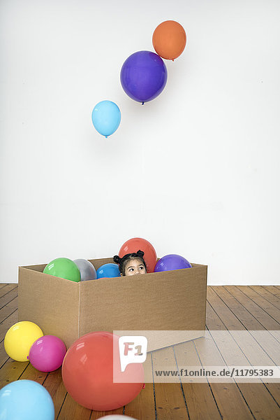 Mädchen im Karton mit Luftballons