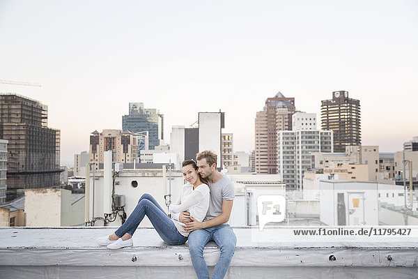 Romantisches Paar sitzt auf der Dachterrasse und genießt die Aussicht.