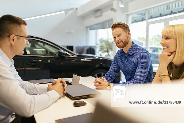 Salesperson advising couple in car dealership