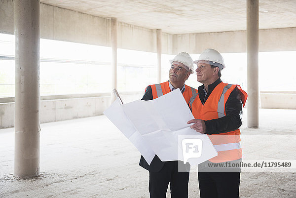 Zwei Männer mit Plan tragen Sicherheitswesten im Baugewerbe