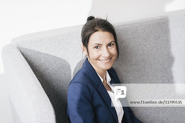 Porträt einer lächelnden Geschäftsfrau auf einer Couch