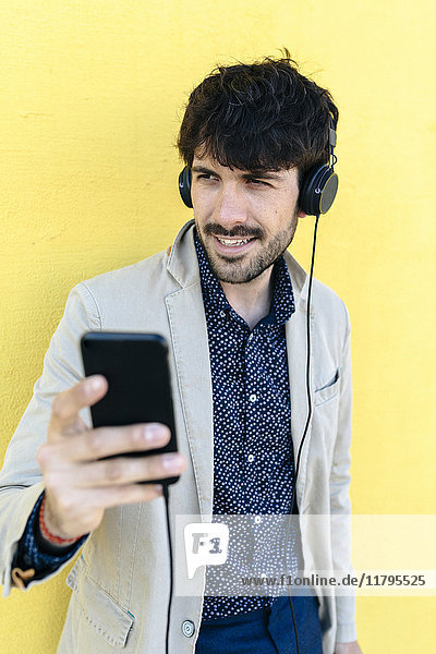 Portrait eines jungen Mannes mit Kopfhörer und Handy