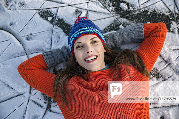 Porträt einer glücklichen Frau  die auf dem gefrorenen See liegt.