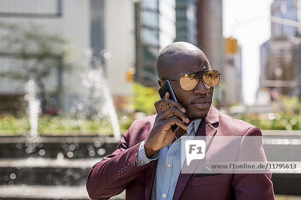 USA  New York City  Manhattan  portrait of businessman wearing mirrored sunglasses on the phone