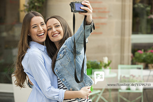 Lachende Freundinnen  die einen Selfie auf der Straße nehmen.