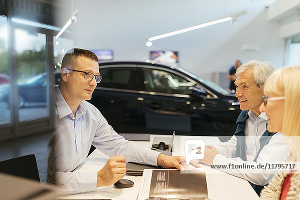 Salesperson advising couple in car dealership