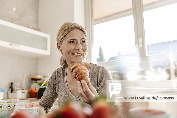 Woman at home eating a croissant