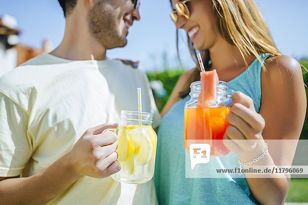 Couple holding refreshing drinks outdoors