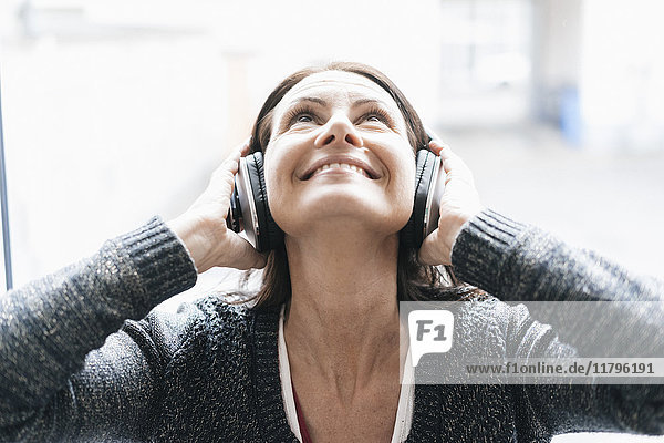 Portrait of smiling woman listening music with headphones looking up