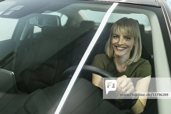 Blonde Frau wählt neues Auto im Autohaus