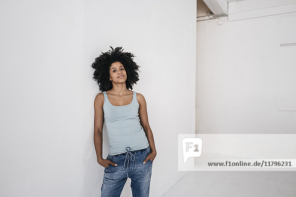 Young woman leaning aginst white wall  looking pensive