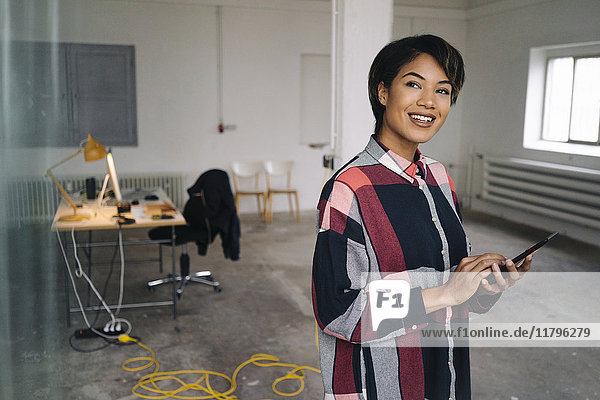 Lächelnde Frau mit Tablette im leeren Büro