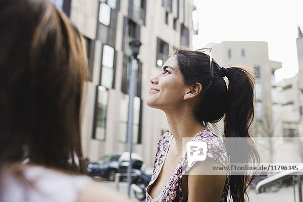 Smiling young woman in the city looking up