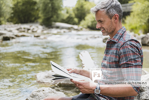Wanderer am Flussufer sitzend  Karte lesen