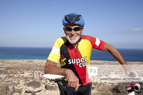 Spanien  Kanarische Inseln  Fuerteventura  lächelnder Senior mit Mountainbike