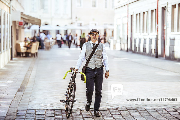 Mature businessman pushing bicycle in the city