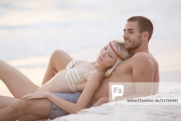 Young couple sitting on the beach  embracing