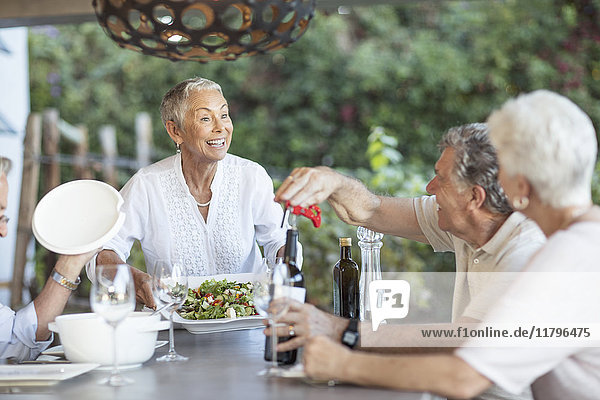 Lächelnde Seniorin beim Mittagessen auf der Terrasse