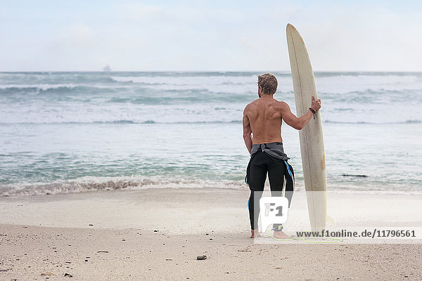 Mann am Strand mit Surfbrett