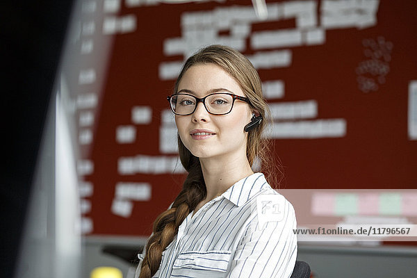 Portait of young woman in office wearing headset