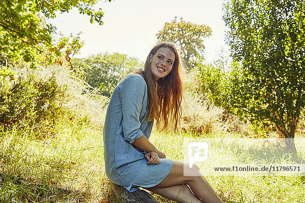 Portrait of smiling young woman sitting on a meadow