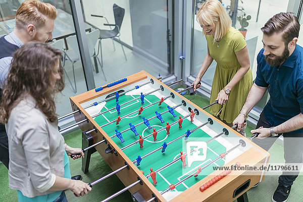 Colleagues playing foosball in office