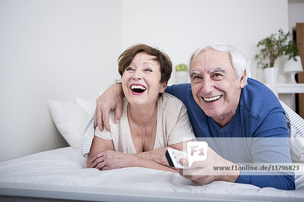 Seniorenpaar im Bett liegend mit Fernbedienung