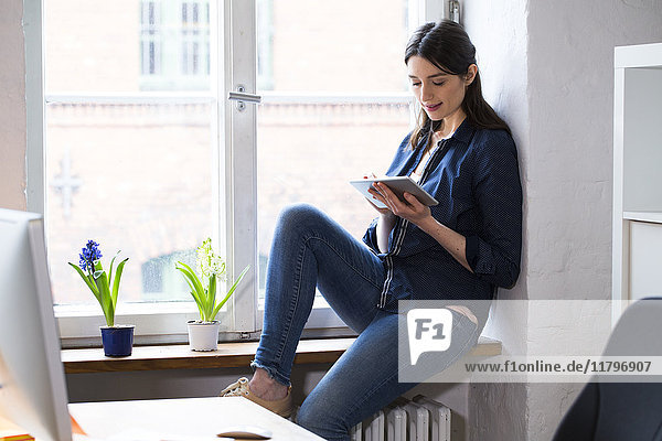 Woman using tablet at the window in office