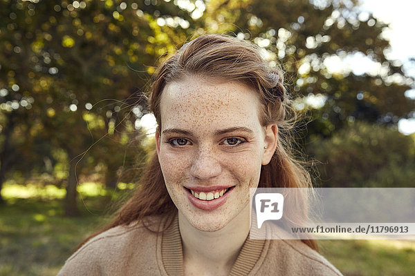 Porträt einer lächelnden rothaarigen jungen Frau mit Sommersprossen