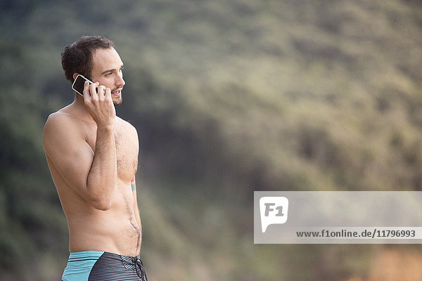 Ein Mann  der am Strand mit dem Handy telefoniert.