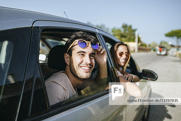 Happy young man and woman in a car looking out the window