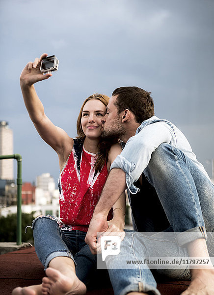 A couple posing for a selfie on a city rooftop.