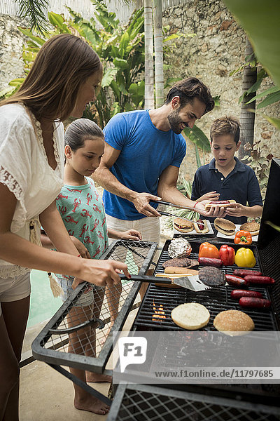 A family standing at a barbecue cooking food.