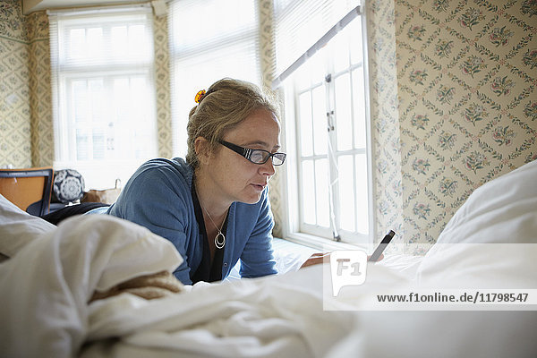 Woman using cell phone on bed