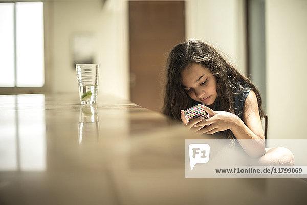 Ein Mädchen sitzt und schaut auf den Bildschirm eines Mobiltelefons.