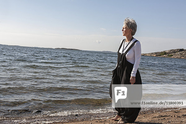 Mature woman on beach looking at sea
