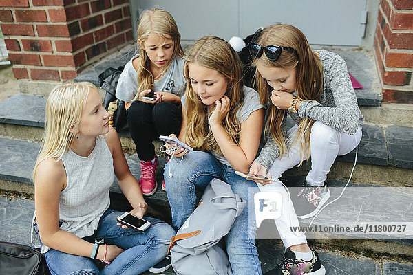 Mädchen sitzen auf Stufen und benutzen Handys