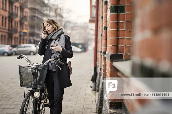Junge Frau mit Fahrrad beim Telefonieren