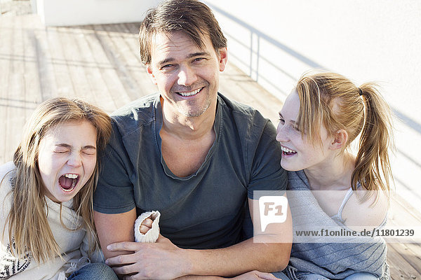 Vater lacht mit zwei Töchtern