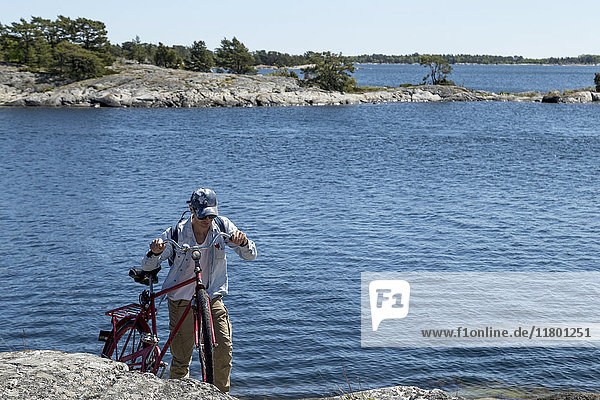 Mann mit Fahrrad am Wasser