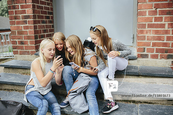 Mädchen sitzen auf der Treppe und benutzen ein Mobiltelefon